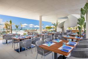 a restaurant with tables and chairs with a view of the ocean at Grupotel Conil Playa - Adults Only Recommended in Conil de la Frontera