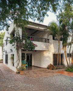 a white house with a palm tree and a patio at Hotel La Casona Del Valle in Valledupar