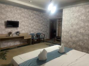 a bedroom with a bed and a desk and a tv at GLOBUS Avenue Hotel in Yakkasaray