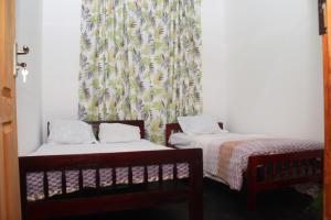 two twin beds in a room with a curtain at Riverside Bliss Cottage in Demodera