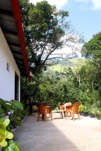 a patio with a table and chairs and trees at Riverside Bliss Cottage in Demodera