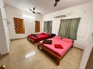 two beds in a room with red sheets at Jamath Villas 1307 in Kīlakarai +4 photos