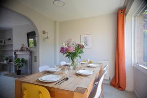 a dining room table with a vase of flowers on it at Hereford Long Term Comfortable Accommodation, 4 bedrooms with Parking in Hereford