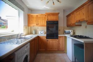 a kitchen with wooden cabinets and a stove top oven at Hereford Long Term Comfortable Accommodation, 4 bedrooms with Parking in Hereford
