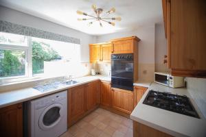 a kitchen with wooden cabinets and a washer and dryer at Hereford Long Term Comfortable Accommodation, 4 bedrooms with Parking in Hereford +21 photos