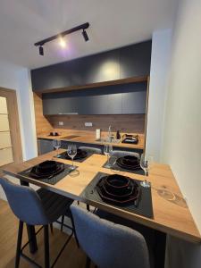 a kitchen with a table with plates and wine glasses at Apartman Raj VV sa garazom Vrnjačka Banja in Vrnjci +14 photos