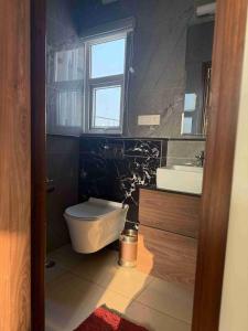 a bathroom with a toilet and a sink and a window at Pacation Home Stay in Noida