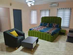 a bedroom with a green bed and a chair at Dipo Apartments in Badore