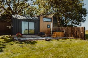 a black tiny house in a yard with a fence at Tiny Bali spa house in Menaldum