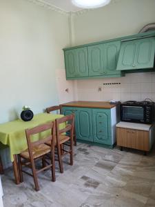 a kitchen with green cabinets and a table with chairs at Livanos Apartments in Neapoli Voion +7 photos