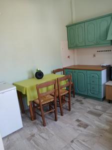 a kitchen with green cabinets and a table and chairs at Livanos Apartments in Neapoli Voion