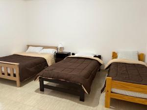 a bedroom with two beds and a white wall at Suarez home in Puerto Madryn