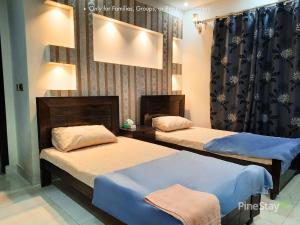 a room with two beds and a mirror at Pine Stay Premium 3 Bedroom Furnished Family Home in Lahore