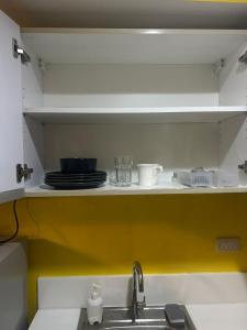 a kitchen shelf with plates and cups and a sink at Sunbeam - Lush Residence in Manila +8 photos