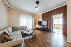 a living room with a couch and a flat screen tv at The Old-Clock Apartment by PikHost in Shkodër