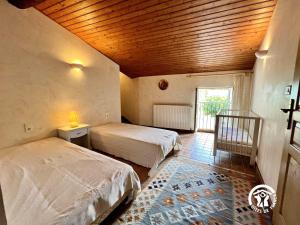 a bedroom with two beds and a wooden ceiling at Domaine de la calm in Villardonnel