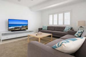 a living room with a couch and a tv at Golden Beach Oceanfront 3BR in Golden Beach +24 photos