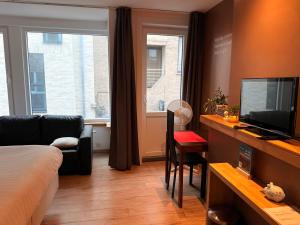 a room with a bed and a tv and a couch at Logies Zen aan Zee in Ostend