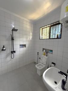 a white bathroom with a toilet and a sink at Dana's Room in Dar es Salaam