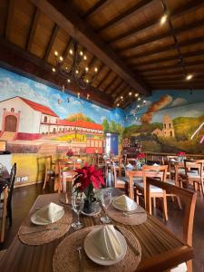 a dining room with tables and chairs and a mural at PASEO REAL HOTEL BOUTIQUE in Uruapan del Progreso