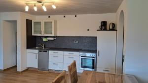 a kitchen with white cabinets and a sink and a table at FeWo Beim Huber in Hopferau