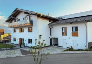 a white house with a balcony on it at FeWo Beim Huber in Hopferau