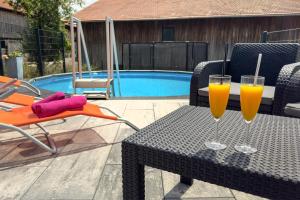 two glasses of orange juice on a table next to a pool at FeWo Beim Huber in Hopferau +8 photos