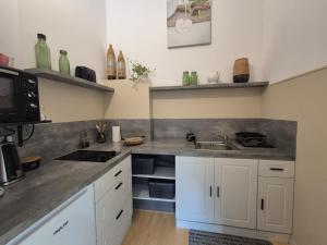 a kitchen with white cabinets and a sink at la longère angevine in Juigné-sur-Loire +14 photos