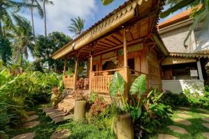 a wooden house with a porch in a garden at Umah Merta Kayu in Ubud