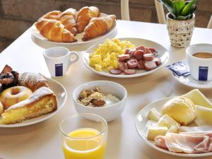 a table with plates of breakfast food on it at B&B HOTEL Imperia Rossini al Teatro in Imperia