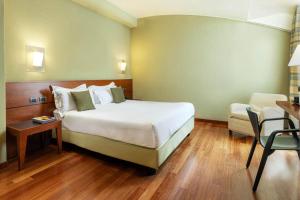 a bedroom with a bed and a desk and a chair at B&B HOTEL Imperia Rossini al Teatro in Imperia