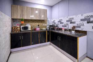 a kitchen with black cabinets and a microwave at Private 2BD Apartment Opposite Dha Phase 8 in Lahore