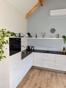 a kitchen with white cabinets and a wooden floor at Woubrugge Logies in Woubrugge +15 photos
