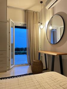 a bedroom with a mirror and a bed and a window at Carpe Diem Suite in Agios Fokas +20 photos