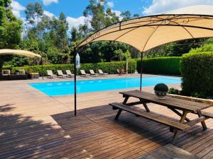 a picnic table with an umbrella next to a pool at Villas do monte in Guimarães