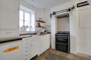 a kitchen with white cabinets and a black stove at 2 Bed in Swanage oc-wy460 in Swanage