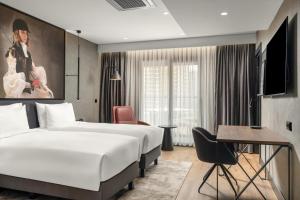 a hotel room with two beds and a desk at Radisson RED Izmir Point Bornova in İzmir