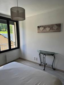 a bedroom with a bed and a table and a window at Le Foirail in Nasbinals