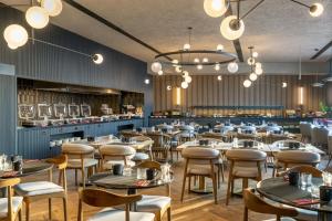 a restaurant with tables and chairs in a room at Radisson RED Izmir Point Bornova in İzmir