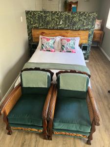 a bedroom with a bed with two green chairs at Grace from Above in Malmesbury +6 photos
