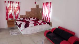 a bedroom with a bed and a red couch at Ecotropicfarmhouse in Cerro Azul