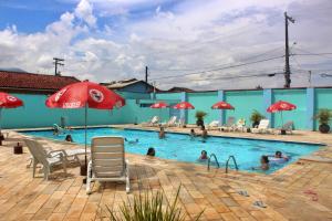 a pool with a red umbrella and chairs and people in it at USCEESP Praia Grande in Praia Grande
