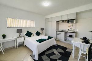 a bedroom with a white bed and a kitchen at Ameni Air B&B in Gqeberha