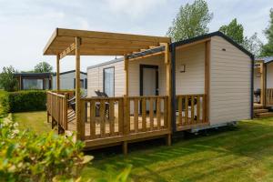 a cabin with a deck and a gazebo at Camping Pomme de Pin in Stella-Plage