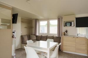 a small living room with a white table and chairs at Camping Pomme de Pin in Stella-Plage