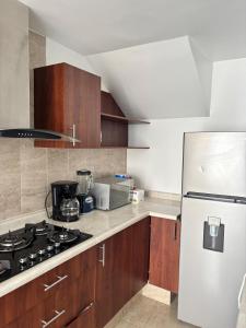 a kitchen with a white refrigerator and wooden cabinets at Hermosa casa familiar con terraza comoda in Xochitepec