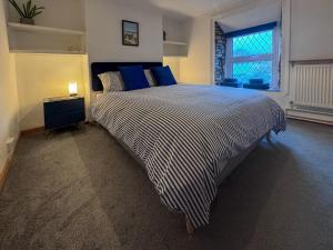 a bedroom with a bed with blue pillows and a window at Arcadia Cottage, Mere in Mere