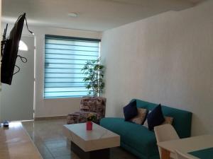 a living room with a green couch and a table at Hermosa casa familiar con terraza comoda in Xochitepec