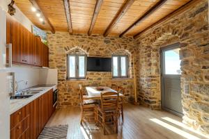 a kitchen with a table and chairs and a stone wall at Stone house koumani in Thalámai