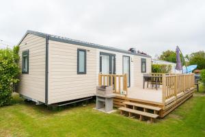 a tiny house with a deck and a table at Camping Pomme de Pin in Stella-Plage +15 photos
